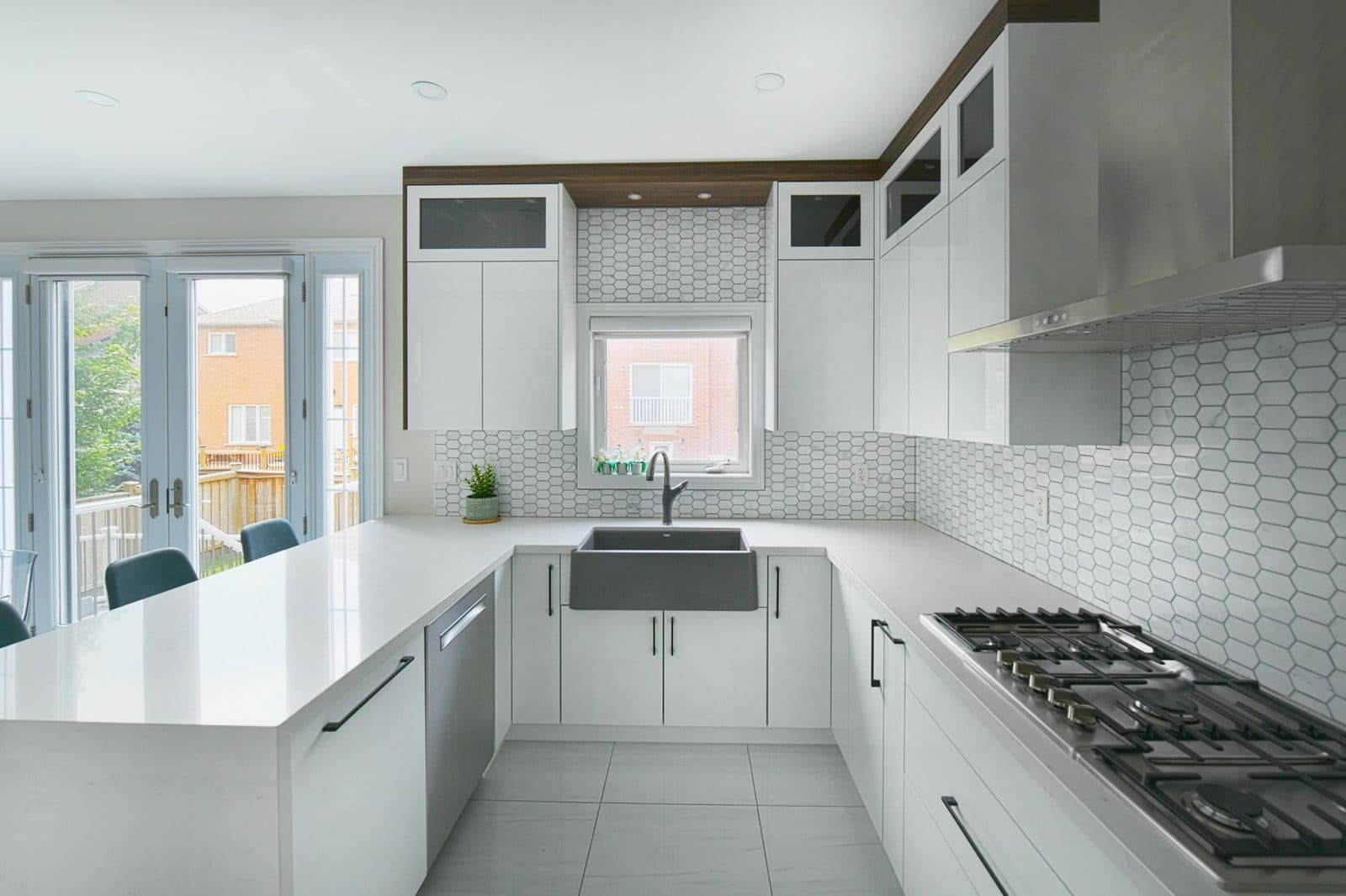 Modern white kitchen with full-height hex tile backsplash, gloss white cabinets, gas cooktop, and large-format floor tile
