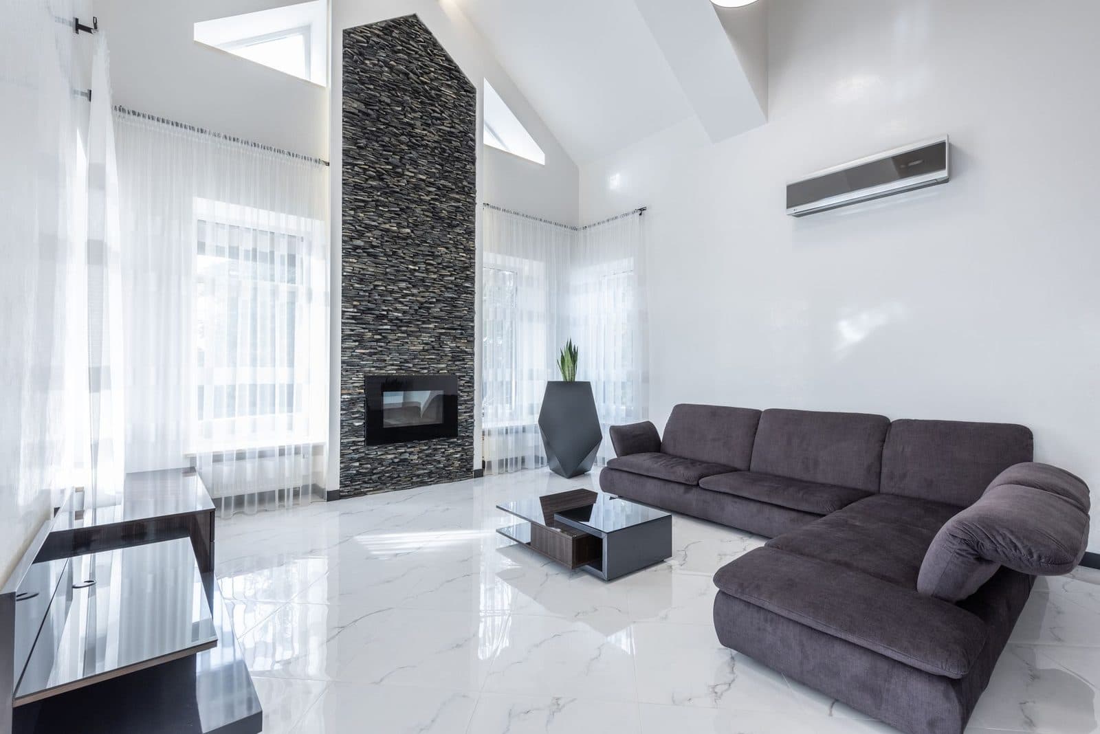 Bright living room with large-format polished white marble floor tiles and a stacked-stone fireplace