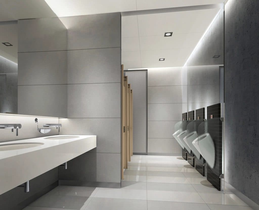 Commercial restroom with large-format gray wall tile, porcelain floor tile, and a solid-surface sink counter